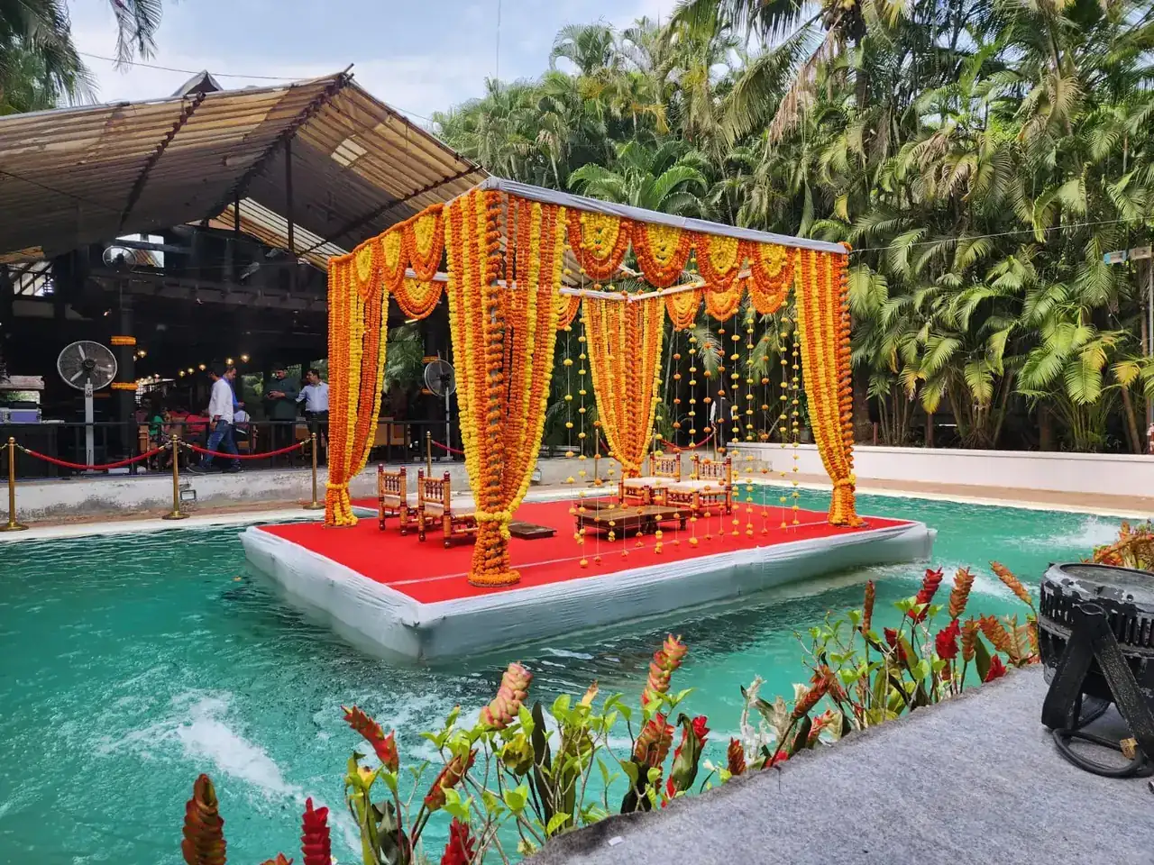 Wide view of the marigold-decorated floating mandap on the pond at Exotica Tropical Retreat