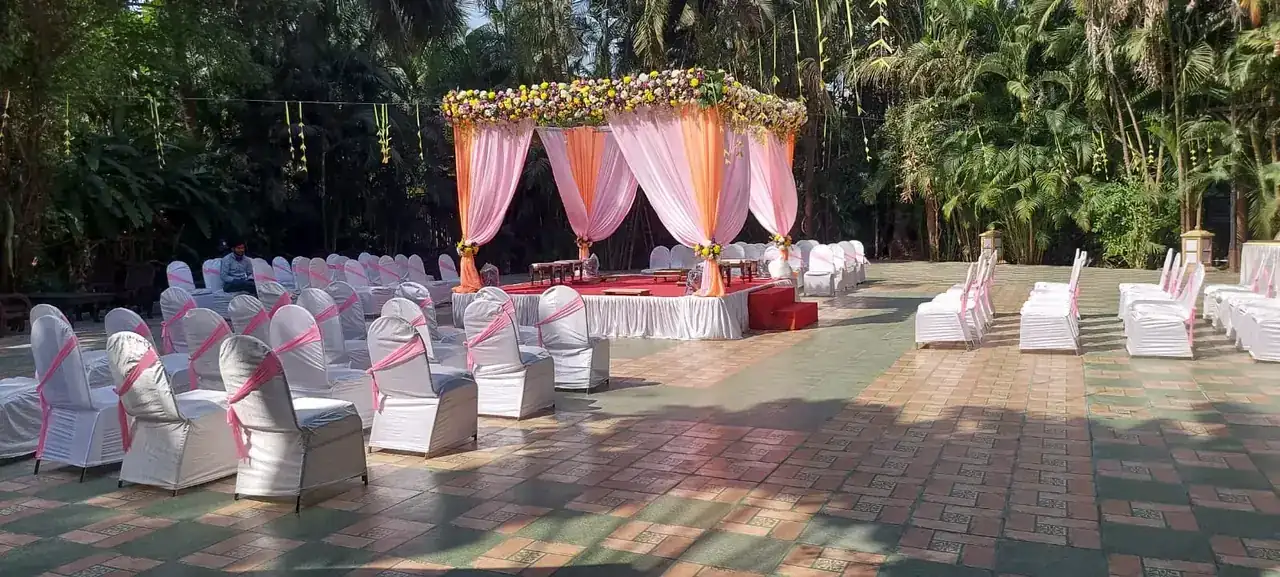 Garden wedding ceremony seating with white chair covers and a floral mandap at Exotica